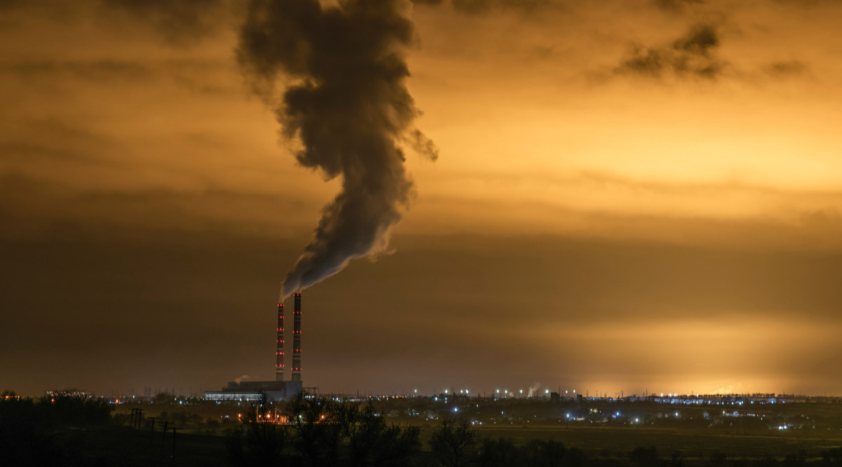 Una planta industrial treu fum sobre una ciutat. Roman Khripkov (Unsplash)