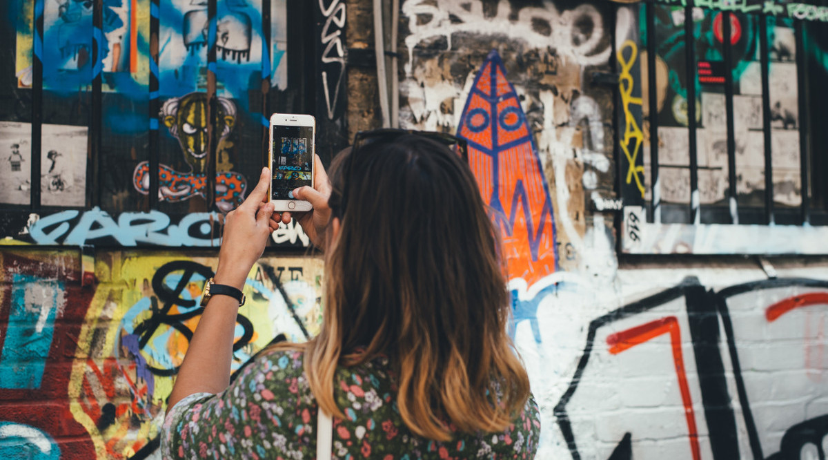 Una dona una fotografia amb el mòbil d'un 'grafitti'. Annie Spratt (Unsplash)