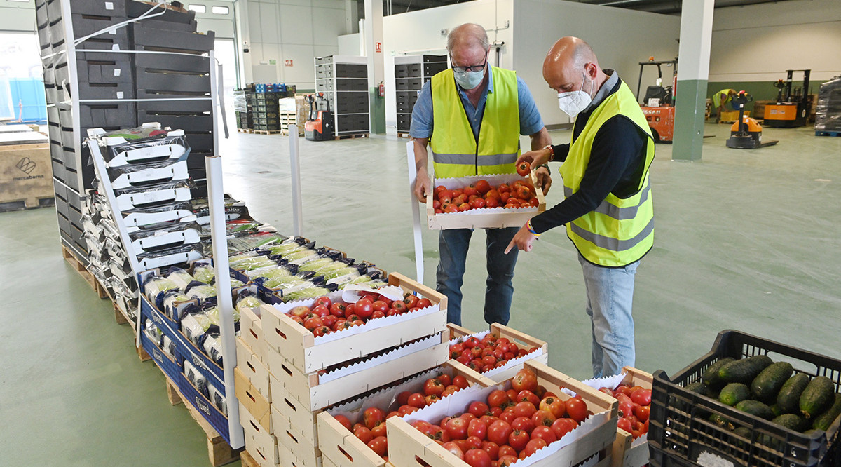 Dos voluntaris del Banc dels Aliments, al rencinte de Mercabarna. ACN